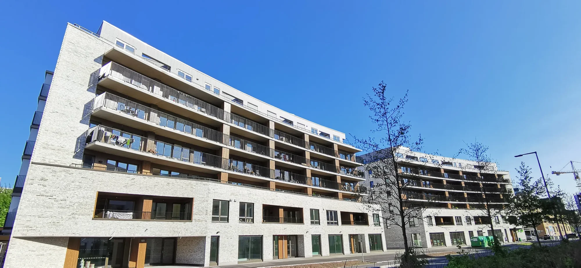 Locus Ensjø, Gladengveien. Fasaden har lys tegl i kombinasjon med malt panel og lys platekledning. Bygningen er buet mot Ellipseplassen. Bygningene leker med form og dybde, med utkragede balkonger, og inntrukne partier.