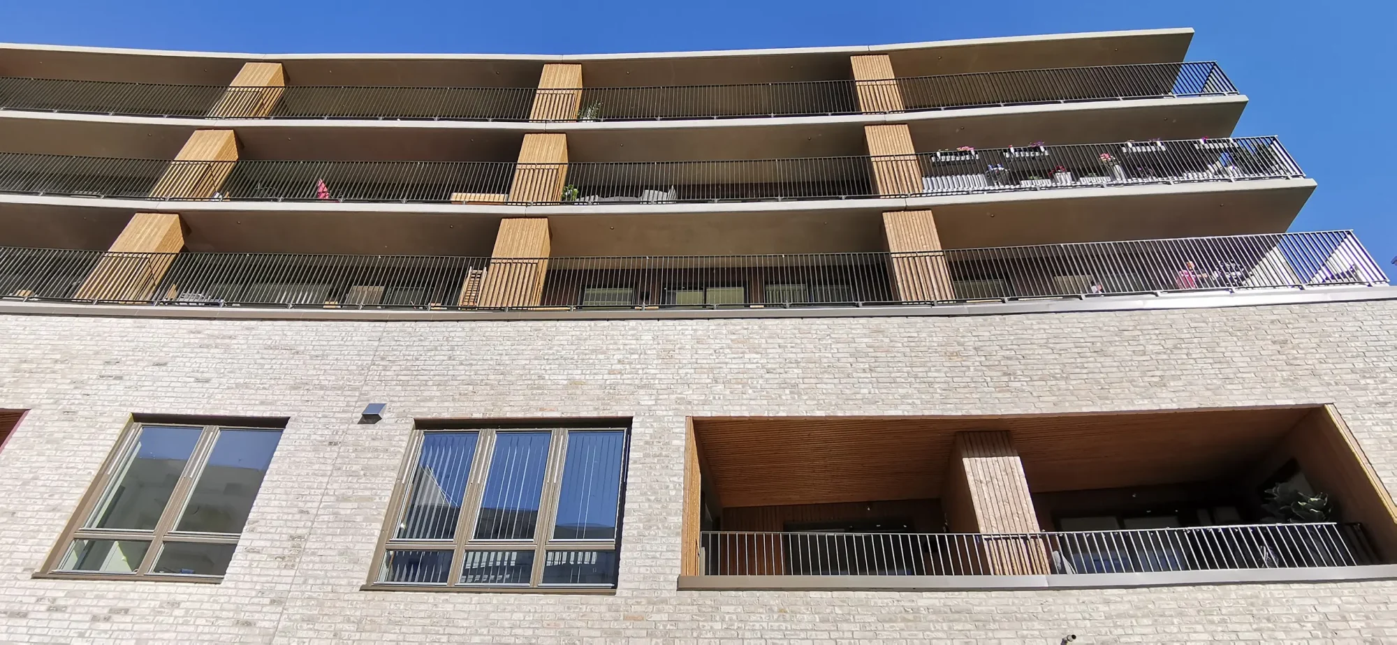 Locus Ensjø, Gladengveien. Fasaden har lys tegl i kombinasjon med malt panel og lys platekledning. Bygningen er buet mot Ellipseplassen. Bygningene leker med form og dybde, med utkragede balkonger, og inntrukne partier.