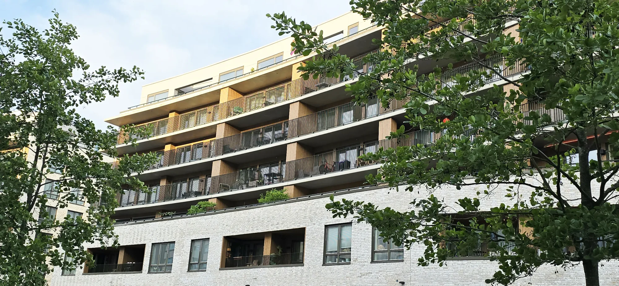 Locus Ensjø, Gladengveien. Fasaden har lys tegl i kombinasjon med malt panel og lys platekledning. Bygningen er buet mot Ellipseplassen. Bygningene leker med form og dybde, med utkragede balkonger, og inntrukne partier.