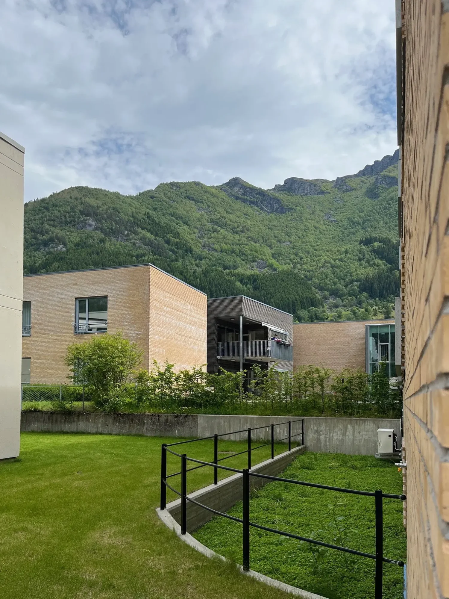 eide omsorgssenter i Ullensvang kommune, odda. bygget er et bærekraftig og framtidsrettet helsehus, med lys brun tegl og store vinduer. bygget ligger i vakre omgivelser, omkranset av høye fjell.