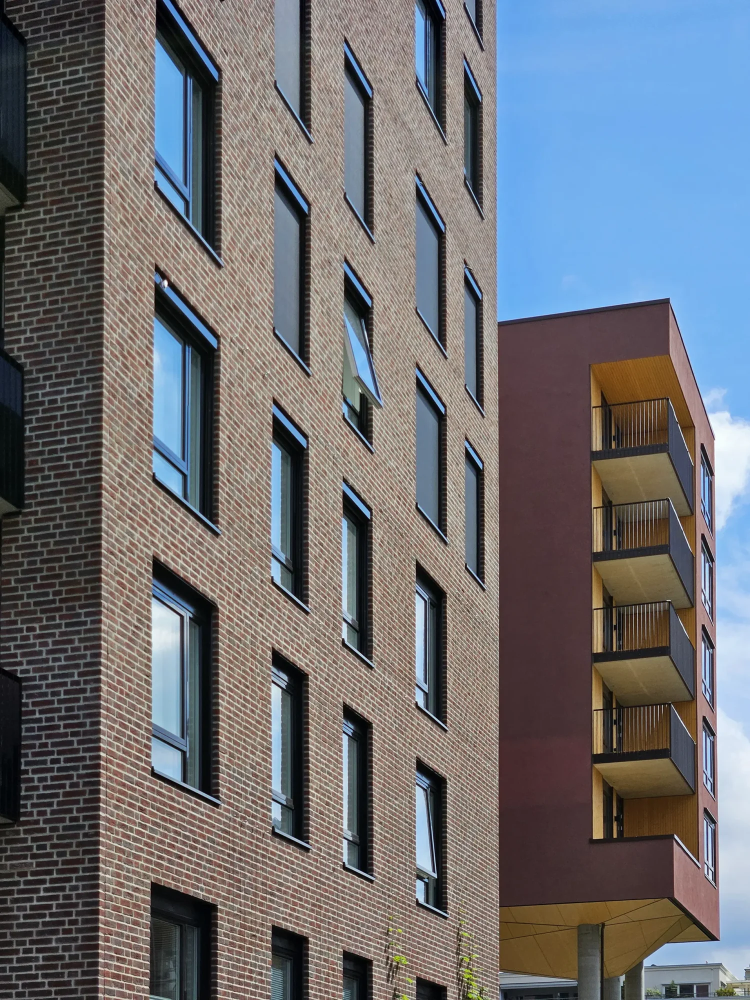 Lille Løren park, teglfasader med innslag av puss i ulike farger, og trekledning. Oppbrutte volumer, og grønne og frodige utearealer.