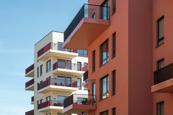 Gårdskvartalet med barnehage på Skårer skårerbyen. fasadene har rød/ rosa puss, farget balkongrekkverk, og farget beslag på dekkeforkanter, slik at balkongene i større grad er en del av fasadelivet, og gir et skulpturelt uttrykk.