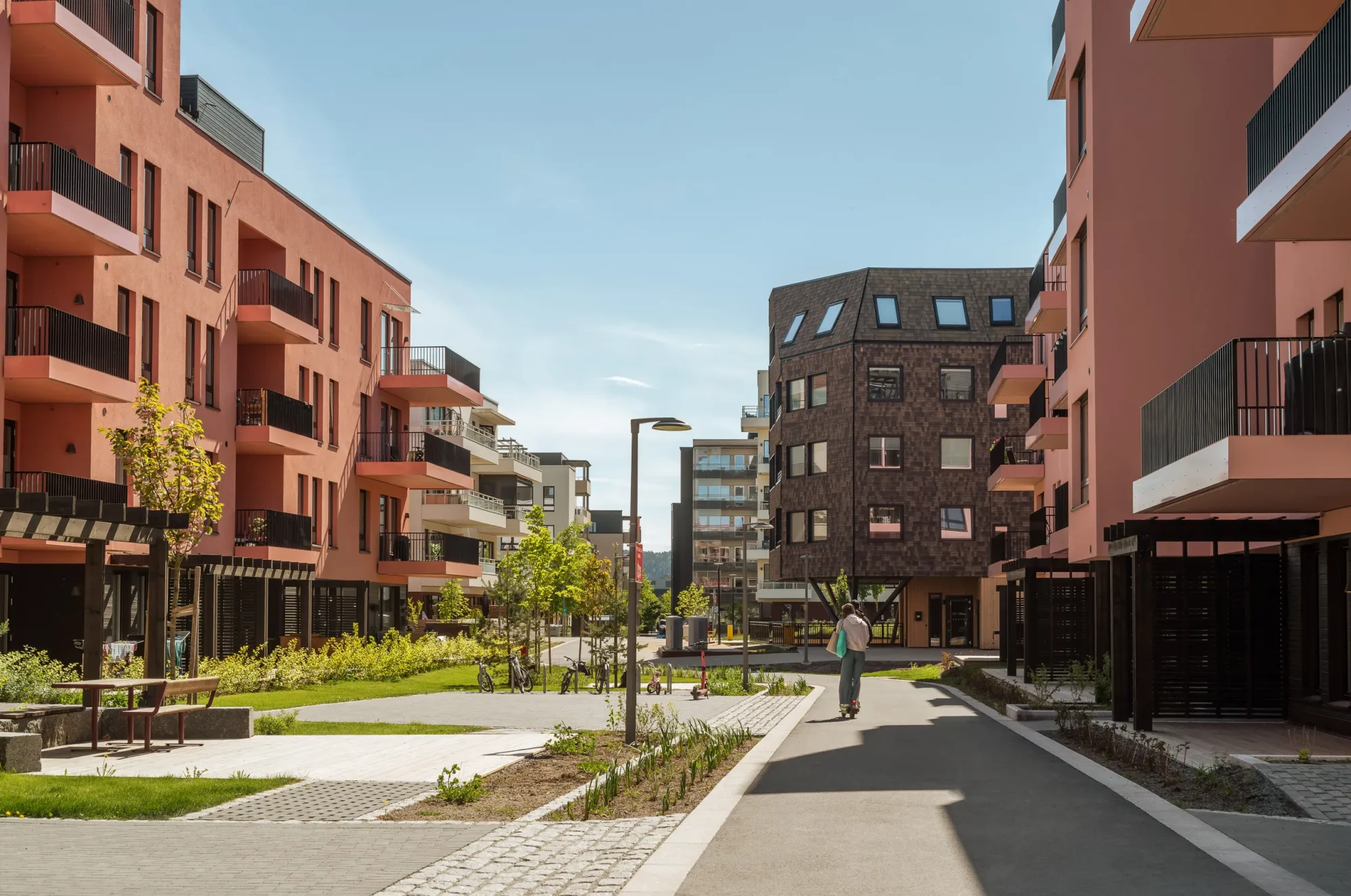 Gårdskvartalet med barnehage på Skårer skårerbyen. fasadene har hvit og rød/ rosa puss, farget balkongrekkverk, og farget beslag på dekkeforkanter, slik at balkongene i større grad er en del av fasadelivet, og gir et skulpturelt uttrykk. Kongla skiller seg ut med mørk brun skjermtegl.