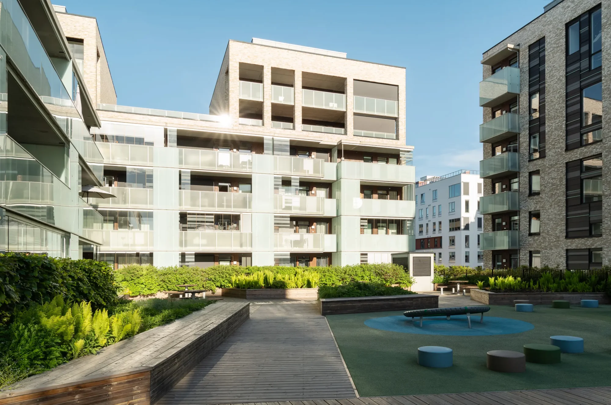 Engebrets promenade, Lillestrøm. Her finnes åpne tilgjengelige torg, og offentlig passasje gjennom kvartalet. Fasadene er utført med lys tegl, sort platekledning, og inntrukne og utkragede balkonger med foliert glassrekkverk som gir varierte dybder og interessant skyggespill.