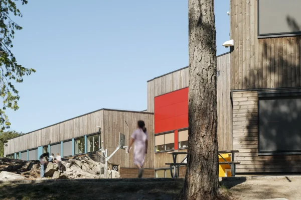 Fjerdingby skole, beliggende i en skog, der vegetasjonen er bevart og ligger helt inntil bygningskroppen. Fasader er utført i behandlet treverk, og har vindusbånd med farget plater i primærfarger, og tydelige innganger.