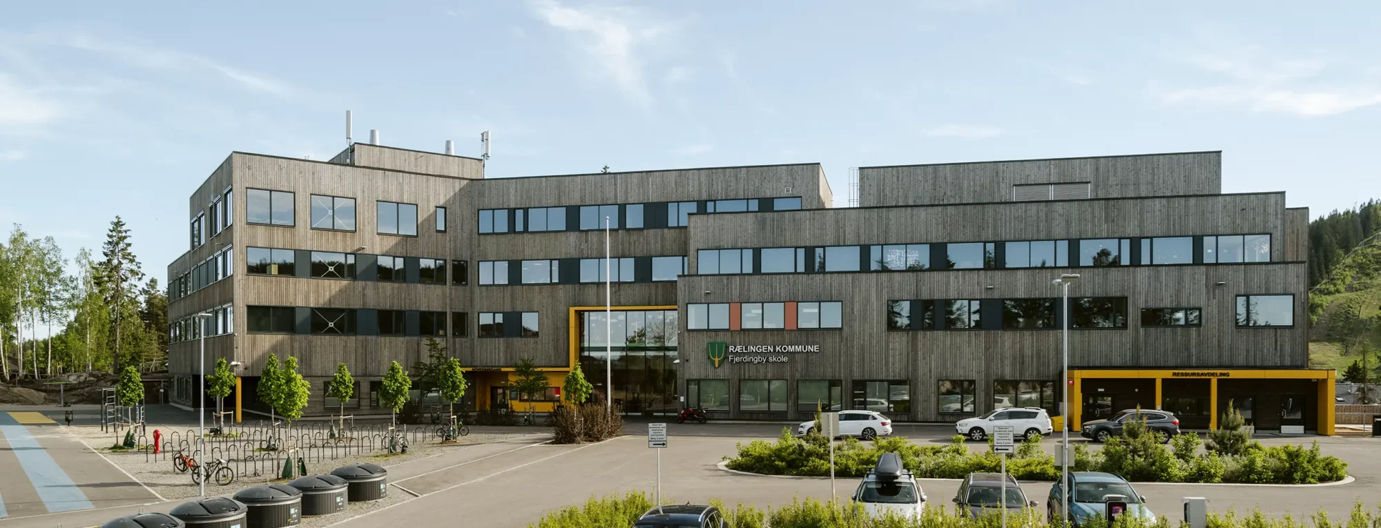 Fjerdingby skole, beliggende i en skog, der vegetasjonen er bevart og ligger helt inntil bygningskroppen. Fasader er utført i behandlet treverk, og har vindusbånd med farget plater i primærfarger, og tydelige innganger.
